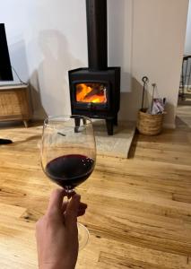 a person holding a glass of wine in front of a fireplace at Beach Escape Torquay in Torquay