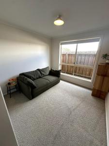 a living room with a couch and a window at Beach Escape Torquay in Torquay