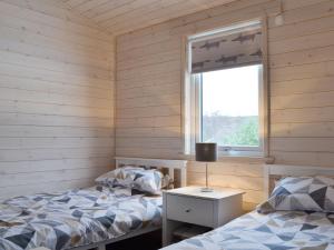 two beds in a room with a window at The Den in Etteridge