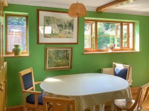 een groene eetkamer met een tafel en stoelen bij Cwmfron House in Llanidloes +27 foto's