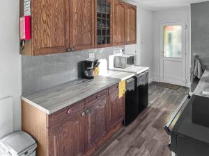 Una cocina con gabinetes de madera y encimera. en Pillango, en Cowes