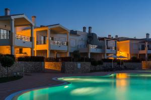 a villa with a swimming pool in front of a building at NAU Salema Beach Village in Salema