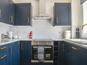 a kitchen with blue cabinets and an oven at Seashell House in Burnham on Sea