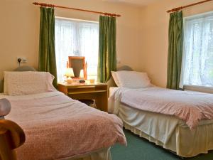 zwei Betten in einem Zimmer mit grünen Vorhängen in der Unterkunft Blackbird Cottage in Llanfair Caereinion + 4 Fotos