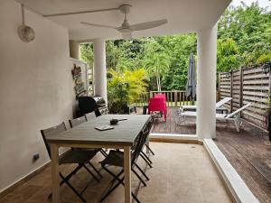 a dining room with a table and chairs on a deck at Antilo - appartement proche mer in Le Diamant
