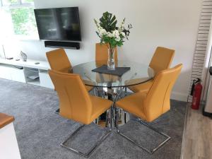 a glass dining room table with orange chairs and a television at Bowness Apartment - Uk11016 in Bowness-on-Windermere