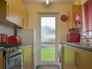 a kitchen with a refrigerator and a window at Talland Bay in Saint Cleer