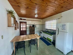 Una cocina con una mesa de madera y un refrigerador. en Casa Paiol Grande, en São Bento do Sapucaí