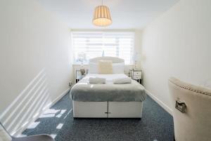 Un dormitorio blanco con una cama y una silla. en 3 Bed House With Free Parking, Garden & Fast Wifi, en Cardiff