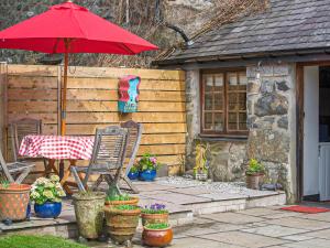 a patio with a table and an umbrella and some plants at Ty Hir-Qc925 in Dolbenmaen +20 photos