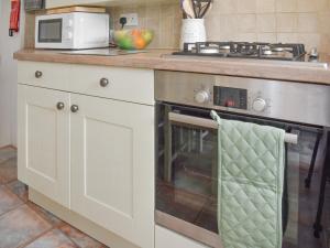eine Küche mit Herd und Mikrowelle in der Unterkunft Gold Cottage in Swaffham + 14 Fotos