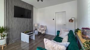 a living room with a green couch and a flat screen tv at O & A Retreat in York