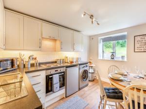 a kitchen with white cabinets and a table and a dining room at Church View Cottage - Uk45697 in Pickering
