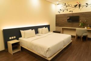 a bedroom with a large white bed and a desk at Grand Permata Hijau Hotel in Sukabumi +5 photos