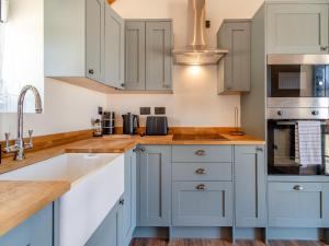 een keuken met blauwe kasten en een wastafel bij Fountain Front Barn - Uk45937 in Corley