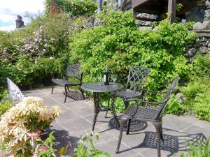 a patio with chairs and a table in a garden at High White Stones in Ambleside
