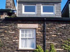 ein Backsteinhaus mit zwei Fenstern darauf in der Unterkunft Alexandra Cottage in Windermere