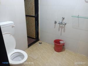 a bathroom with a toilet and a red trash can at Private Room3 At Pushpanjali Residency Phase 2 Ghodbunder Road Ovale Thane West in Kolshet