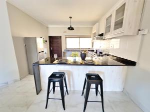 a kitchen with two bar stools and a counter top at Greendale Apartments in Lusaka