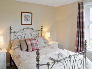 a bedroom with a bed with a plaid pillow at Balcary Mews Cottage in Auchencairn +4 photos