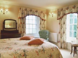 a bedroom with a bed and a mirror and a chair at Laundry Cottage in Uldale +18 photos