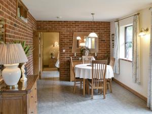 ein Esszimmer mit einem Tisch und einer Ziegelwand in der Unterkunft Riverside Cottage in Costessey