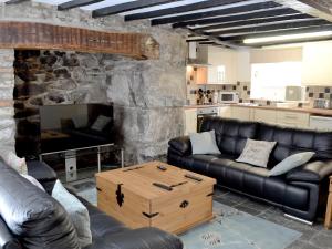 a living room with leather couches and a stone fireplace at Pendref in Trawsfynydd