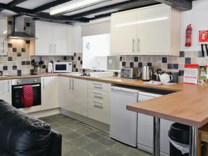 a kitchen with white cabinets and a wooden counter top at Pendref in Trawsfynydd