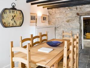 a wooden table with chairs and a clock on the wall at Pendref in Trawsfynydd
