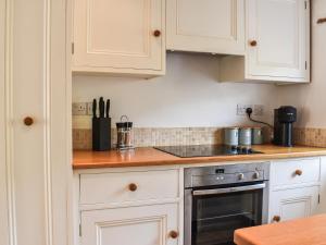 a kitchen with white cabinets and a stove at Dunmallet in Pooley Bridge +21 photos