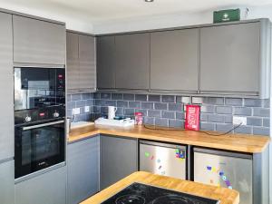 cocina con armarios grises y encimera de madera en Winthorp, en Ivychurch