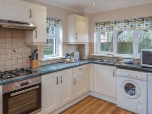 a kitchen with white cabinets and a washer and dryer at Captain's Lodge - Uk6732 in Lydstep