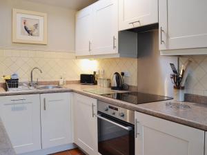 eine Küche mit weißen Schränken und einer Spüle in der Unterkunft Wisteria Cottage in Skirpenbeck