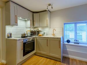 a kitchen with white cabinets and a sink at The Cottage-Uk32854 in Alltwen