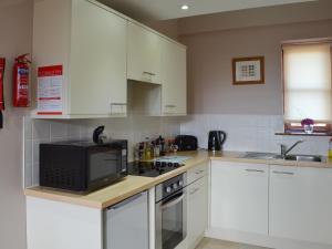 a kitchen with white cabinets and a microwave at Lakeland View in Scotforth