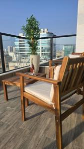 un banc en bois sur un balcon avec une plante en pot dans l'établissement Sunset Home, à Netanya