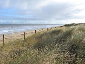 a fence on a beach near the ocean at Violet Cottage in Catfield +2 photos