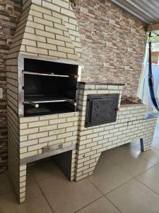 einen Backsteinofen mit Grill in einem Zimmer in der Unterkunft Casa de temporada - PISCINA, FOGÃO A LENHA E CHURRASQUEIRA in Lindóia