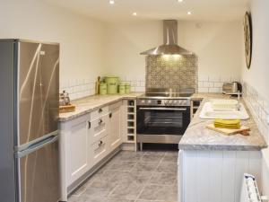 a kitchen with a stove and a refrigerator at Gewans Farm Cottage in St Austell