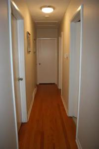 an empty hallway with a white door and wooden floors at Bungalow in Green Area in Ottawa
