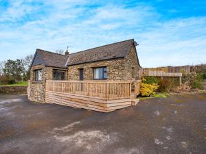 a stone house with a wooden deck in a parking lot at Stable Cottage - Uk10694 in Amroth