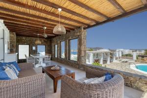 a living room with chairs and a table and a pool at Villa Zanetti Mykonos in Agios Ioannis Mykonos