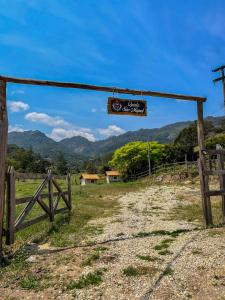 Ein Schild hängt an einem Zaun, im Hintergrund sind Berge zu sehen. in der Unterkunft Chalé Quinta São Miguel 01 - Econômico in Santo Antônio do Pinhal