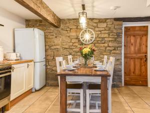 a kitchen with a wooden table with chairs and a refrigerator at Uk45895 - Cross House Cottage in Kirkby Lonsdale