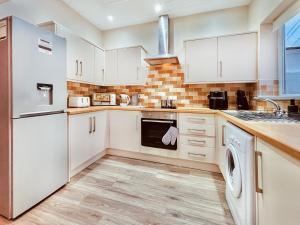 ニュービギン・バイ・ザ・シーにあるRothsay Beach Houseのキッチン(白いキャビネット、洗濯機、乾燥機付)