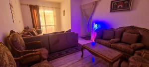 un salon avec deux canapés et une lumière violette dans l'établissement شقه مفروشه بالشروق بالقرب من مدينتى للعائلات و الاسر فقط, à Madīnat aţ Ţalāʼi‘