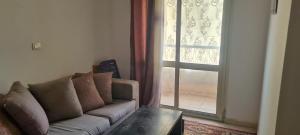 un salon avec un canapé et une grande fenêtre dans l'établissement شقه مفروشه بالشروق بالقرب من مدينتى للعائلات و الاسر فقط, à Madīnat aţ Ţalāʼi‘