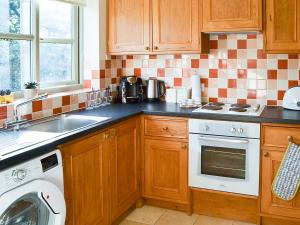 a kitchen with a sink and a washing machine at Lily Broad Cottage in Burgh Saint Margaret