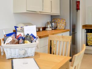 ein Korb mit Lebensmitteln auf einem Tisch in einer Küche in der Unterkunft Boatman's Cottage At Invernian Mor in Inverinan Beg + 13 Fotos