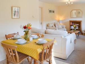 a living room with a table and a couch at Lily Broad Cottage in Burgh Saint Margaret